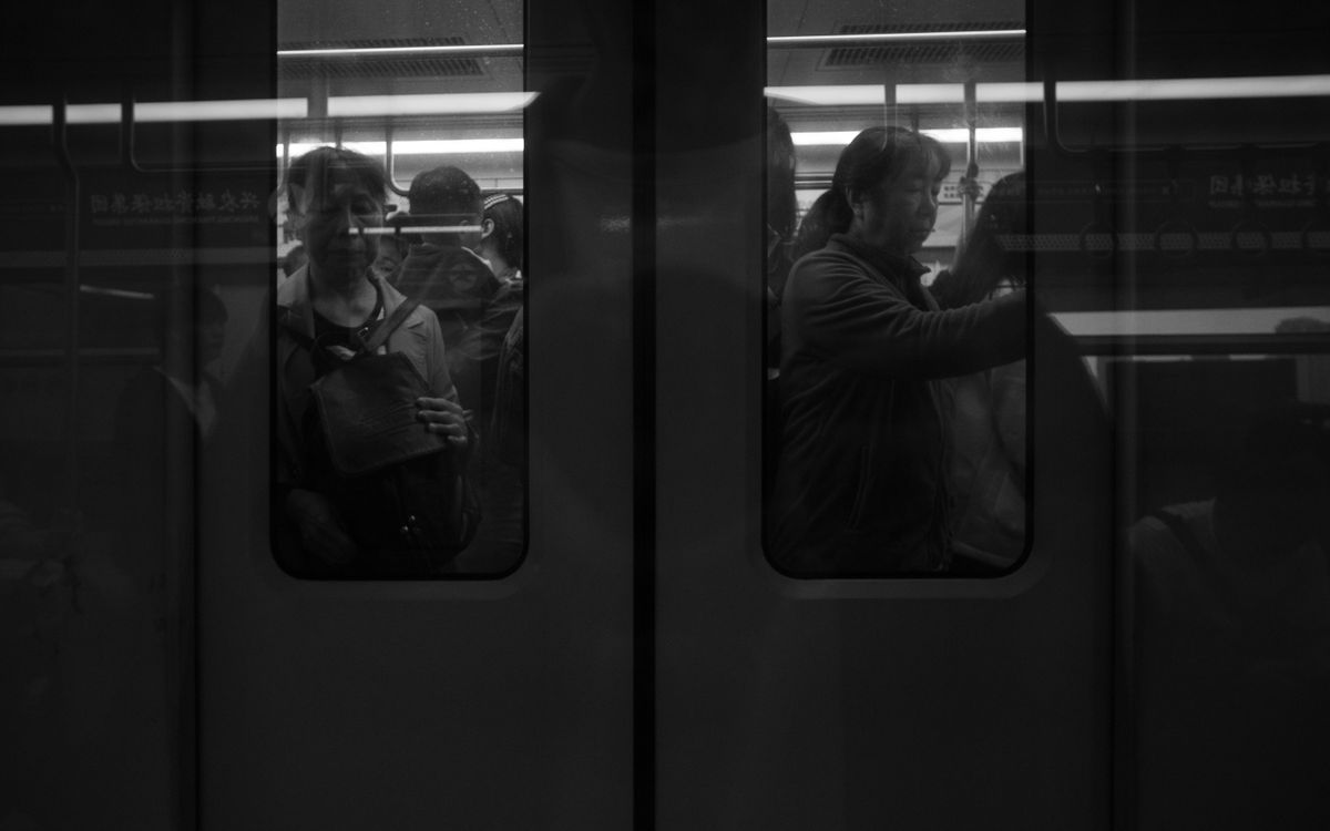 Passengers in a crowded metro train during an urban commute in black and white.