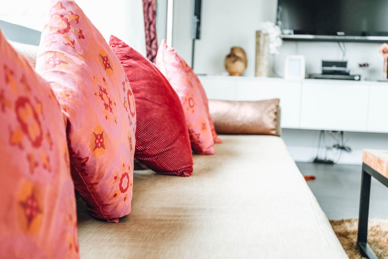 Row of many pink and red cushions lined up on a daybed sofa