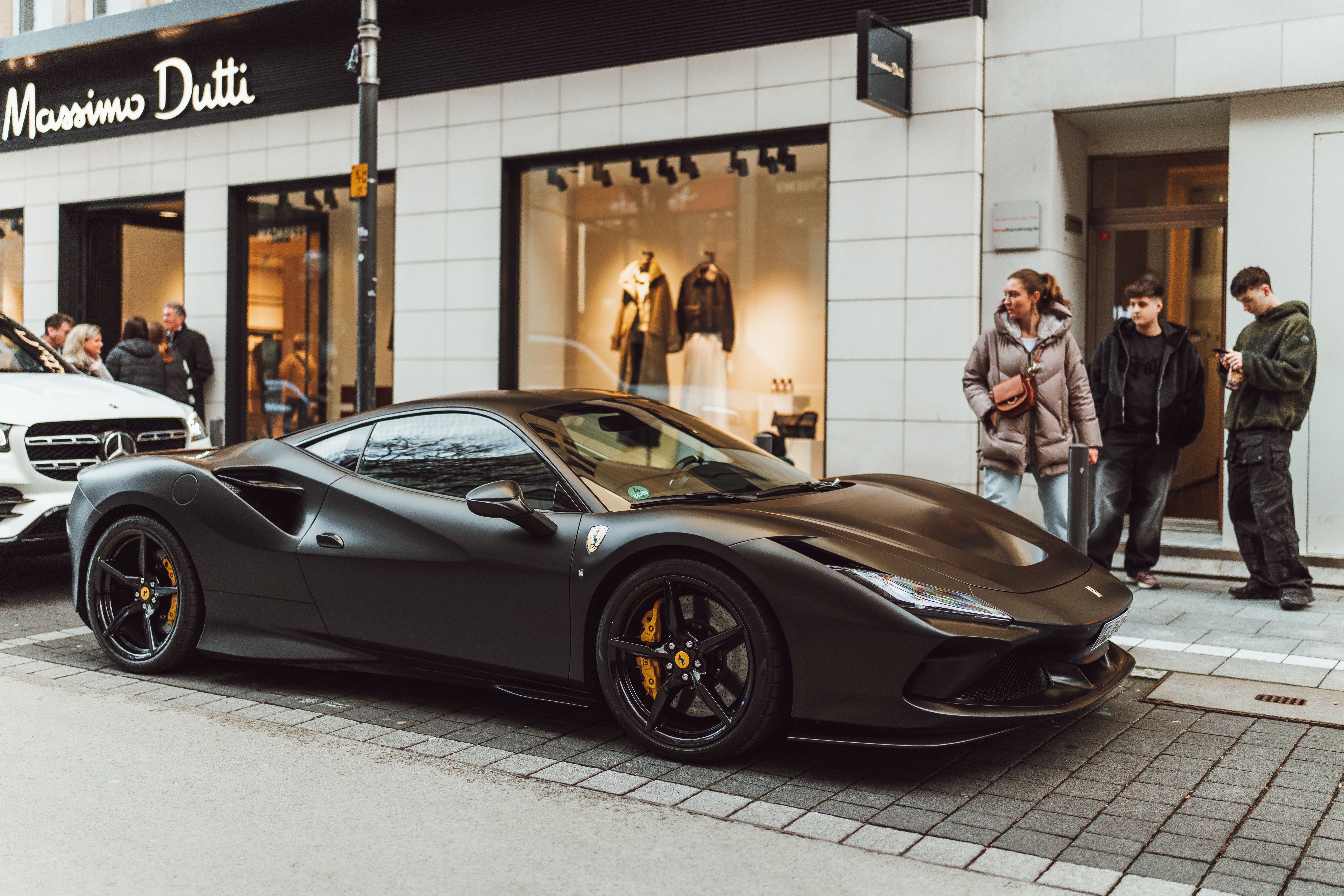 A stylish Ferrari supercar parked outside Massimo Dutti in a bustling city street.