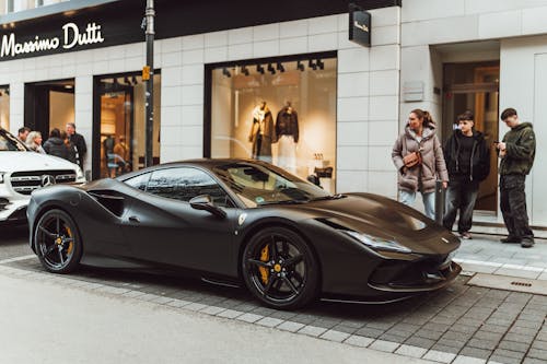 A black ferrari parked on the street in front of a store