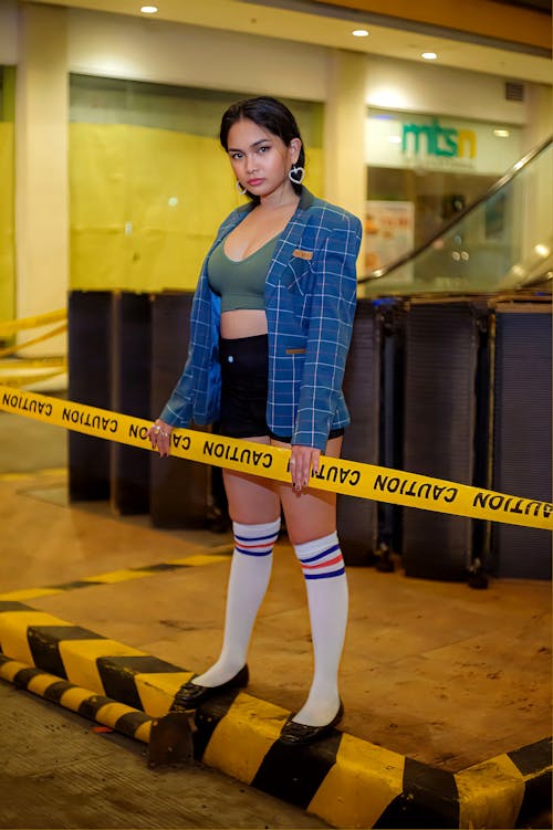Portrait of a Female Model Standing on a Curb Behind a Caution Tape