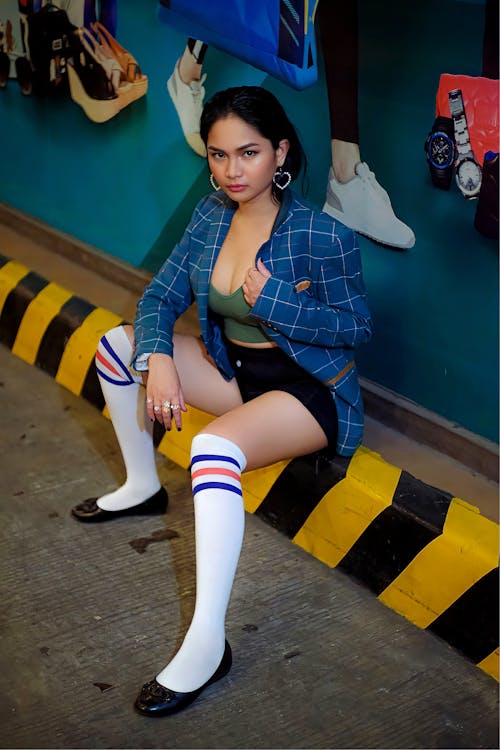 A woman in a blue jacket and white socks sitting on a bench