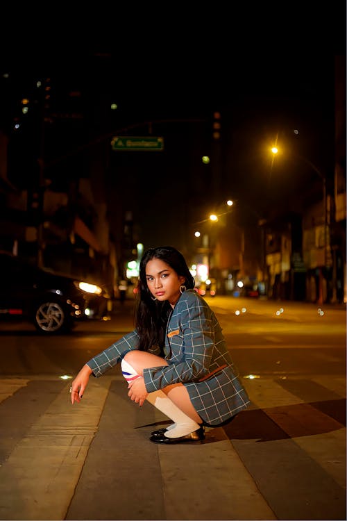A woman kneeling on the street at night