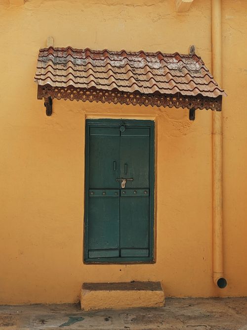 Free Captivating view of a green door with intricate awning against a yellow wall in Mysuru, India. Stock Photo
