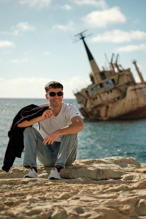 Free Young man smiling by a shipwreck on the Peyia coastline, Cyprus. Stock Photo