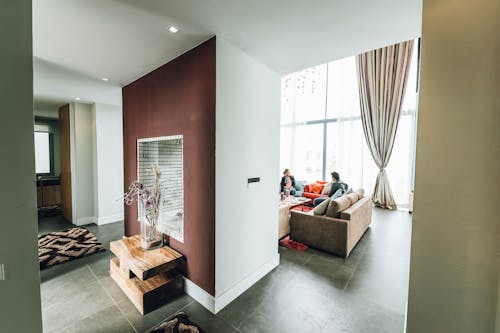 Two Person Sitting on Sofa Beside Glass Wall