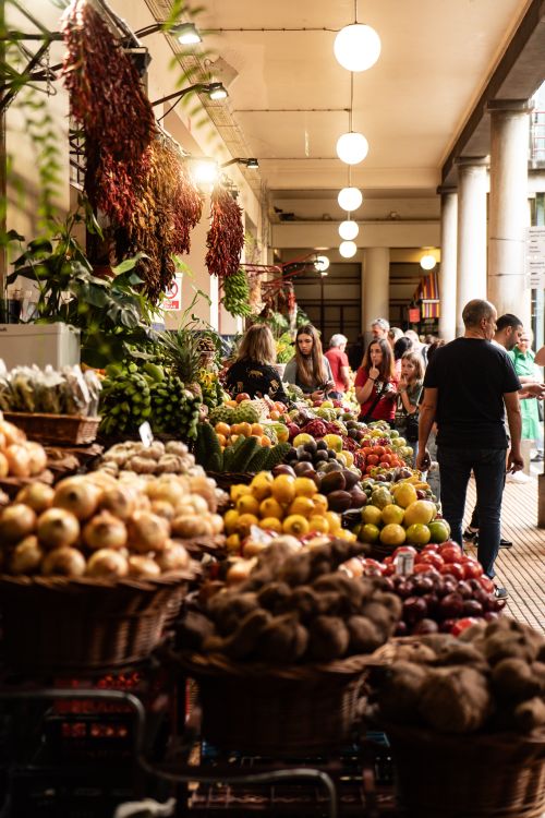 Free A bustling indoor market with diverse fruits and vegetables on display, attracting shoppers. Stock Photo