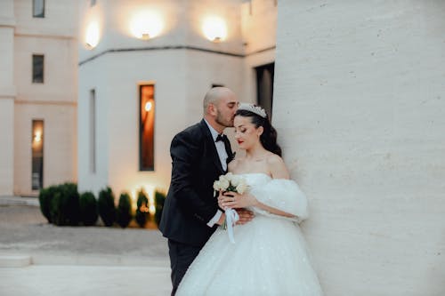 A bride and groom are standing in front of a building