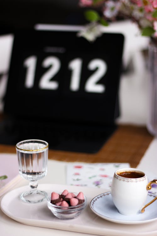 A Cup of Coffee, a Glass of Water and Sweets on a Tray 