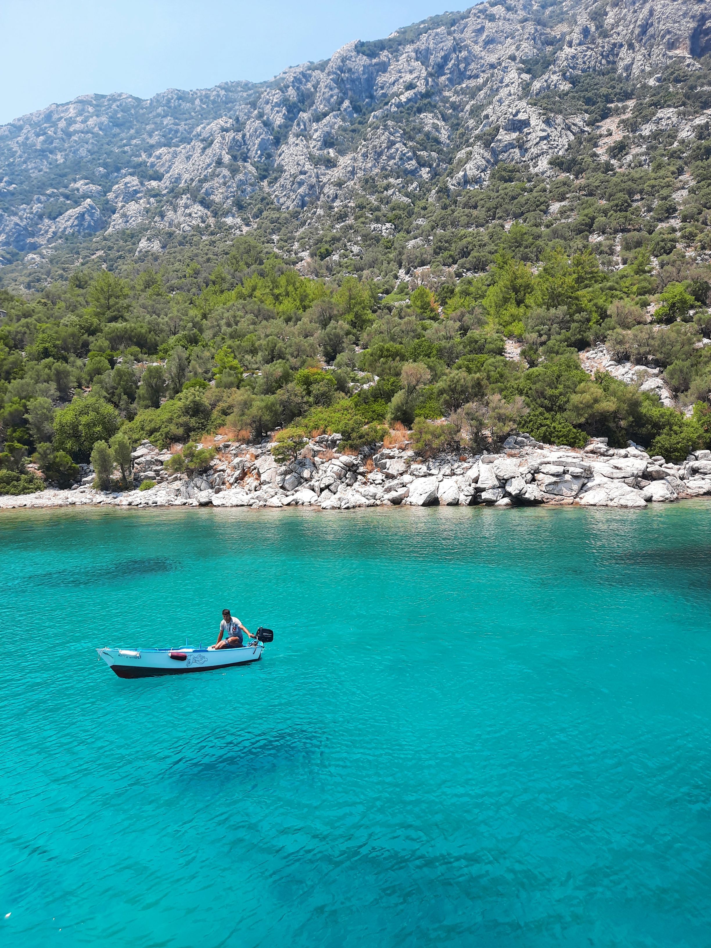 A Person Sitting in a Boat in Turquoise Water · Free Stock Photo