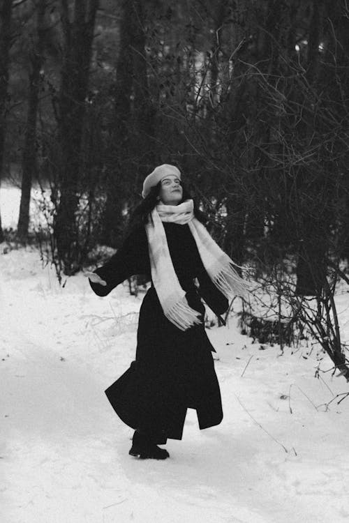 A woman in a long coat and scarf walking through the snow