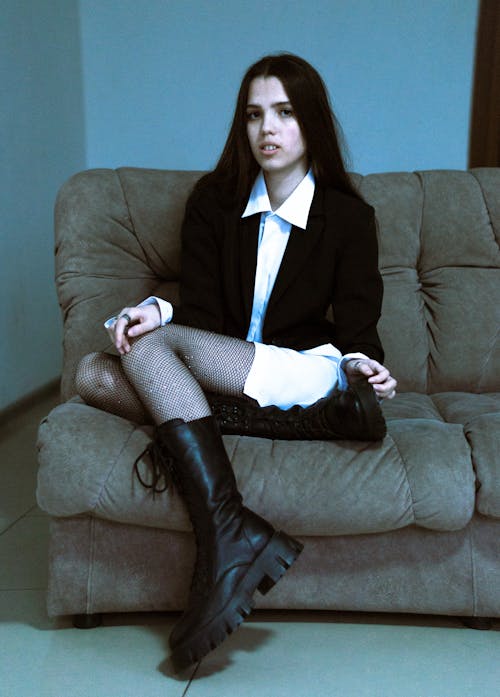 Young Woman in Fishnets and Boots Sitting on a Sofa 