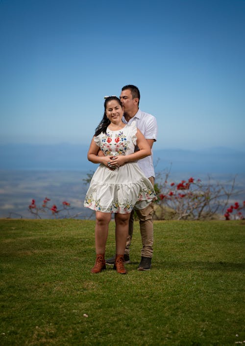 Man Kissing Smiling Woman in White Dress