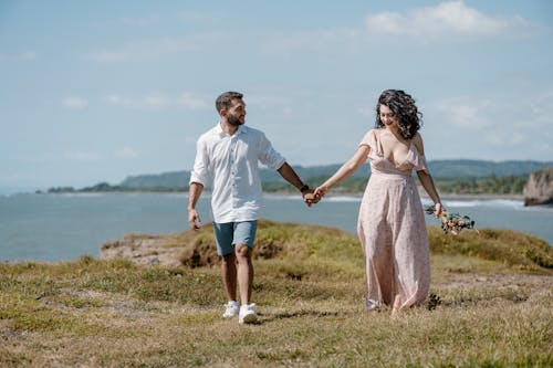 Couple Holding Hands and Walking on Sea Coast