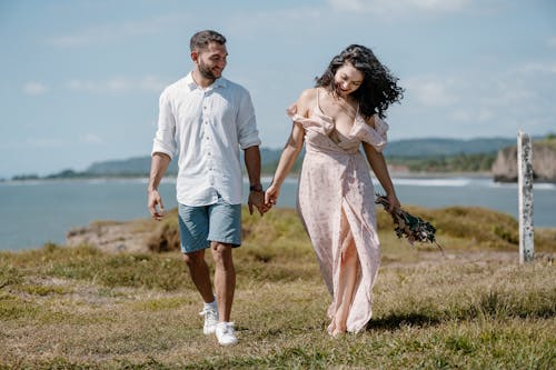 Smiling Couple Holding Hands and Walking on Sea Coast