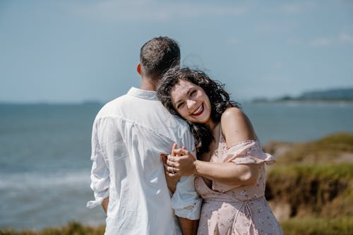 A couple standing by the ocean with their arms around each other