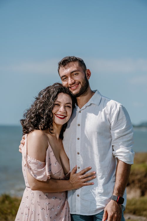 A couple posing for a photo in front of the ocean
