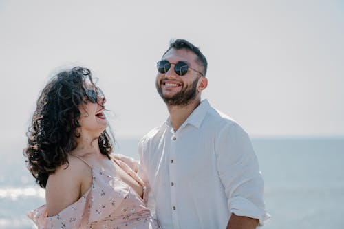 A couple is smiling while standing on the beach