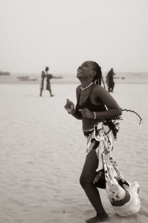 Free A woman joyfully dances on a sandy beach, exuding happiness and freedom. Stock Photo