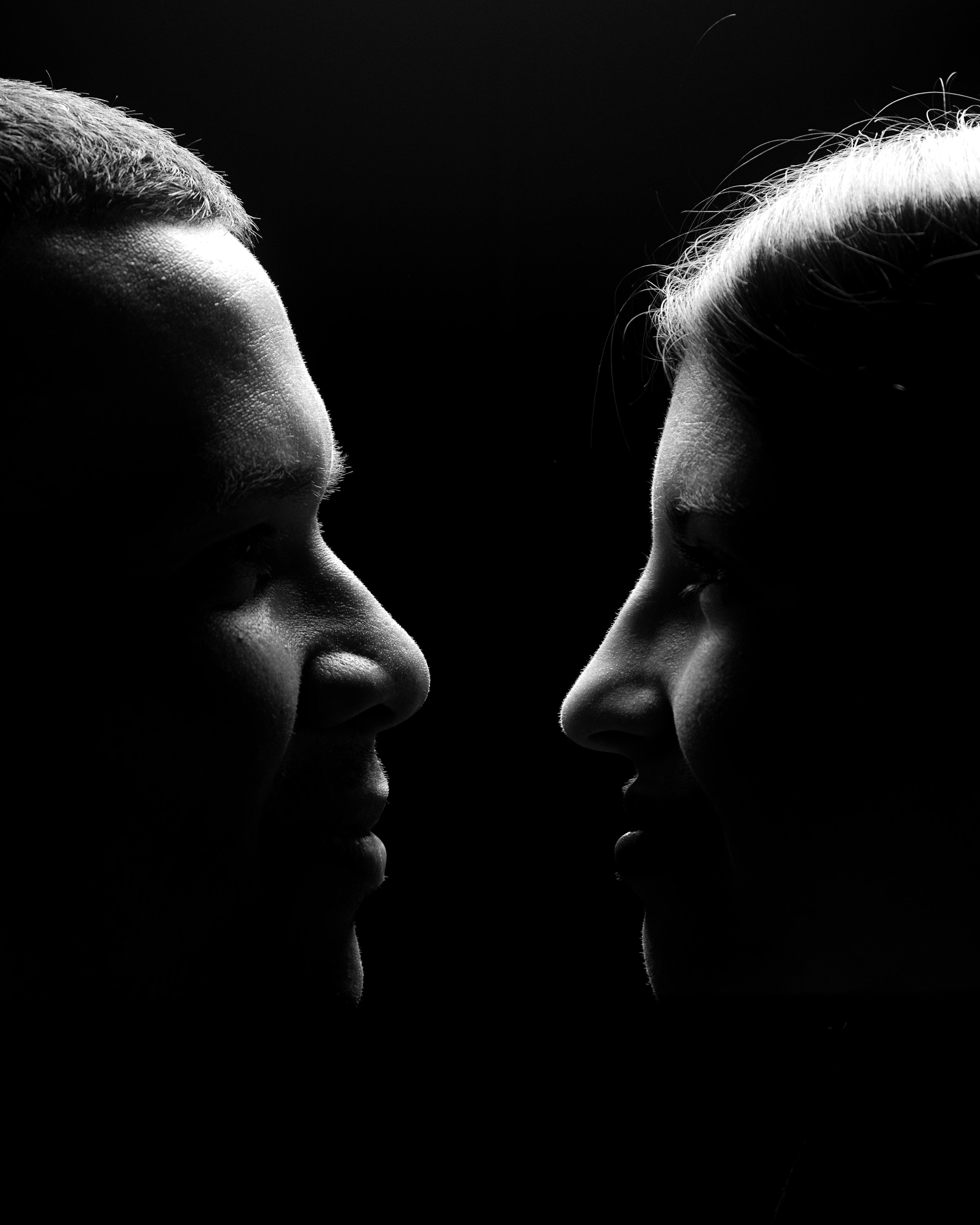 Silhouette of a couple face to face in a black and white studio shot.