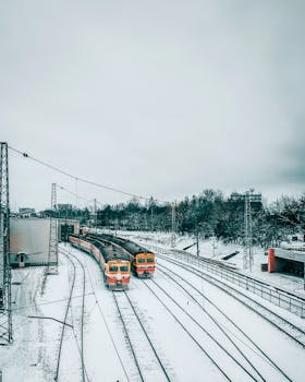 Bright yellow trains on snow-covered tracks at an urban railway station in winter.