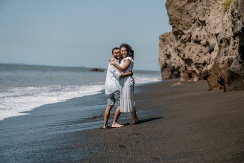 A couple hugging on the beach in front of the ocean