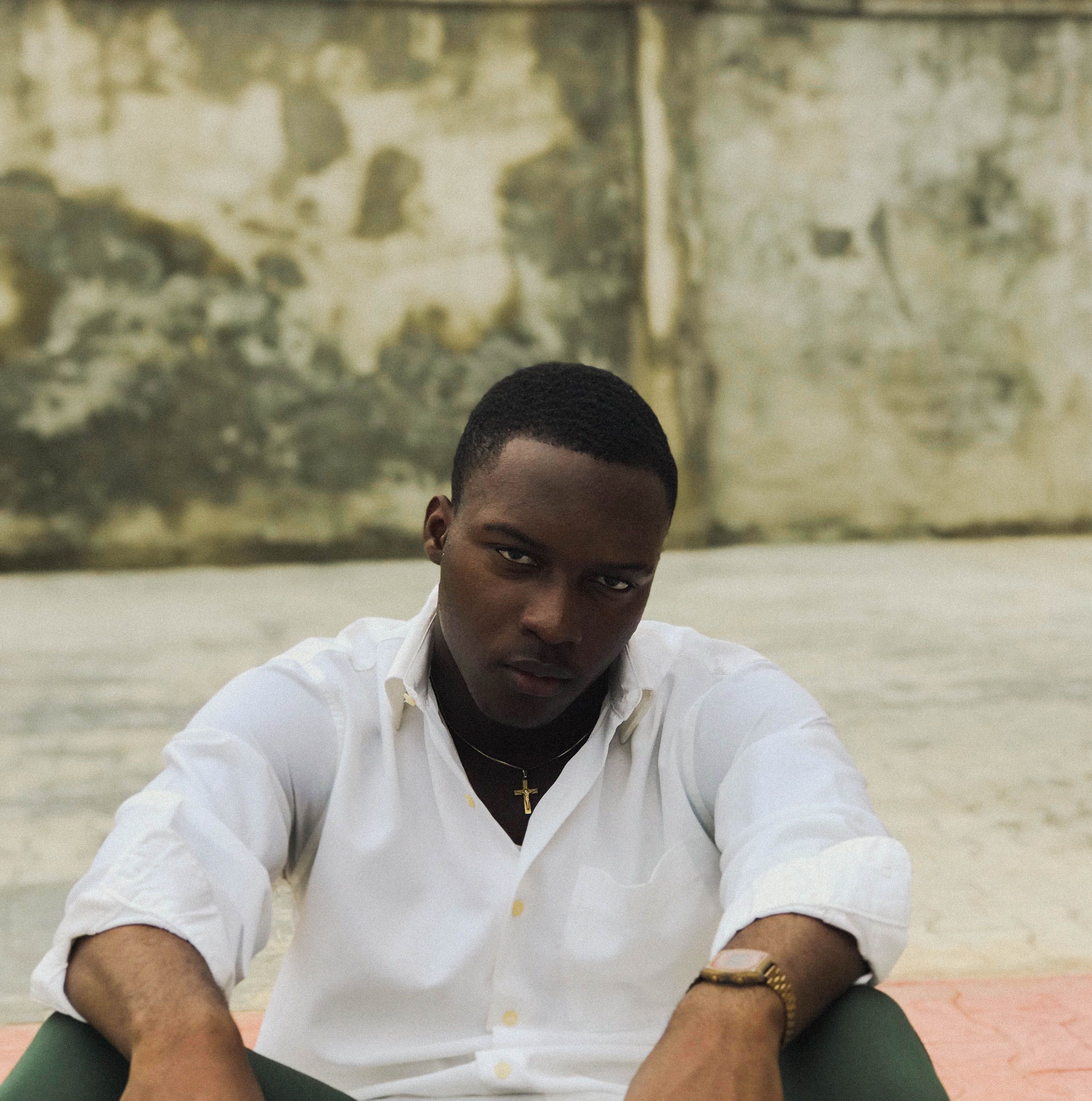 Engaging portrait of a young man in a white shirt against an urban backdrop in Ibadan.