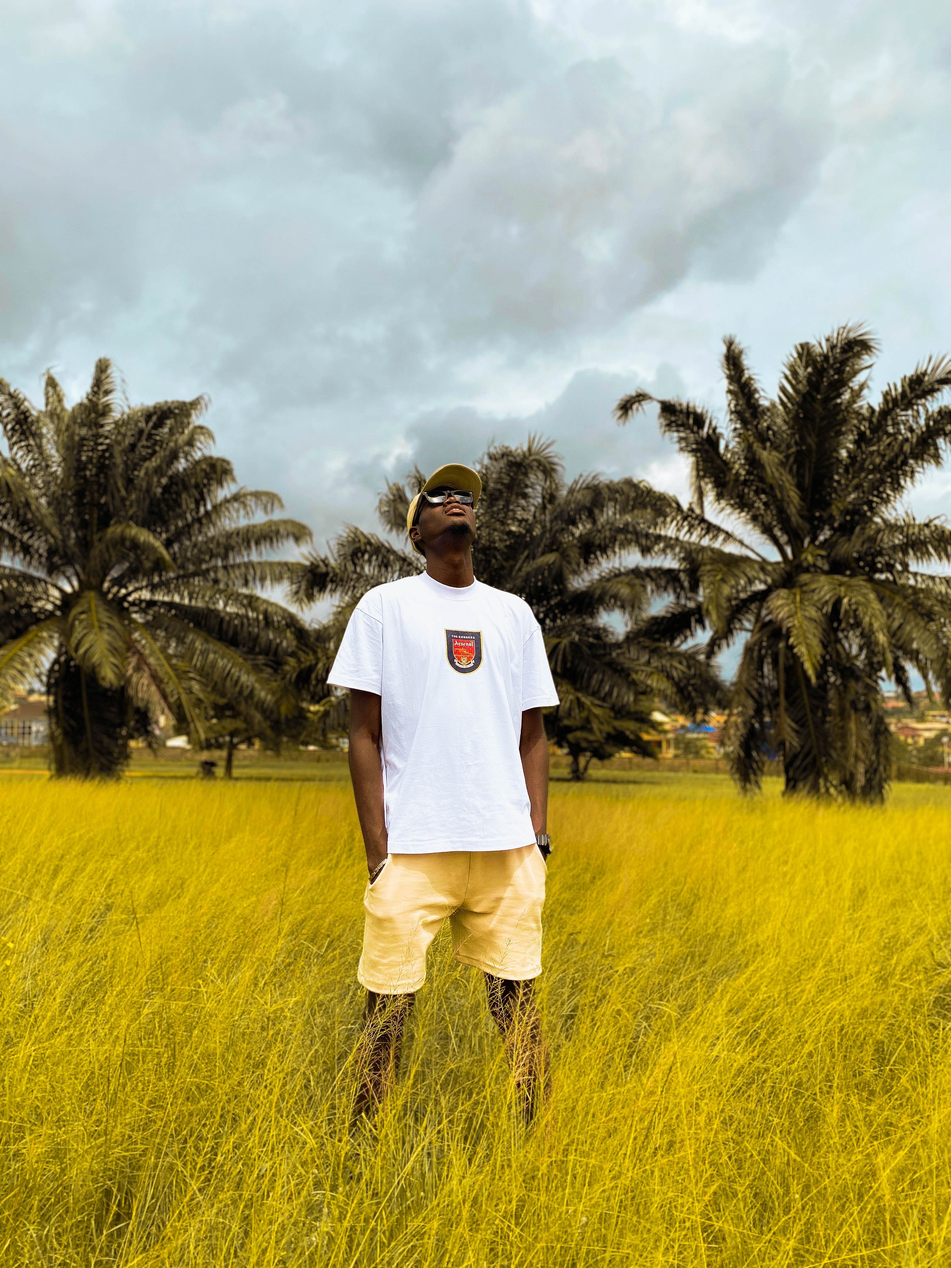 A stylish young man stands confidently in a vibrant Nigerian field, showcasing fashion and culture.