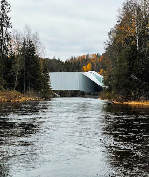 A bridge over a river with trees and a building