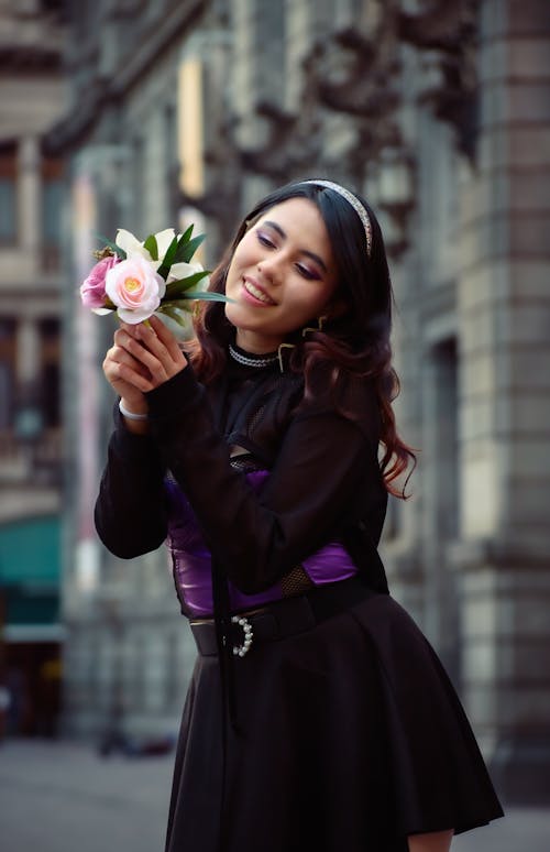 Smiling Woman in Black Dress Standing with Flowers