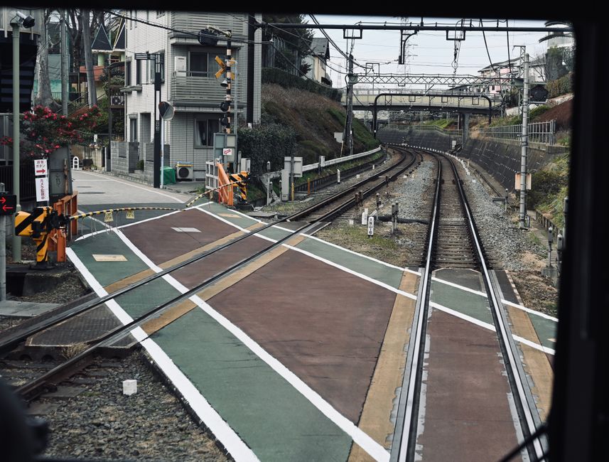 View of a railway crossing in urban area with multiple tracks and buildings.