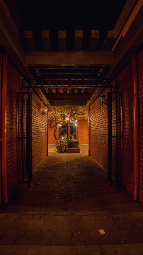 Free A dimly lit corridor leading to a courtyard in San Rafael, California, highlighting warm tones and architectural details. Stock Photo