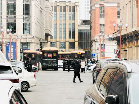 Bustling street in Tianjin, China featuring people, cars, and buses in a vibrant urban setting.
