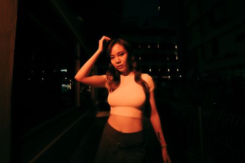 Free A woman in a white top poses at night in Kuala Lumpur, creating a dramatic urban atmosphere. Stock Photo