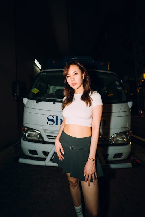 A woman in a skirt standing next to a truck