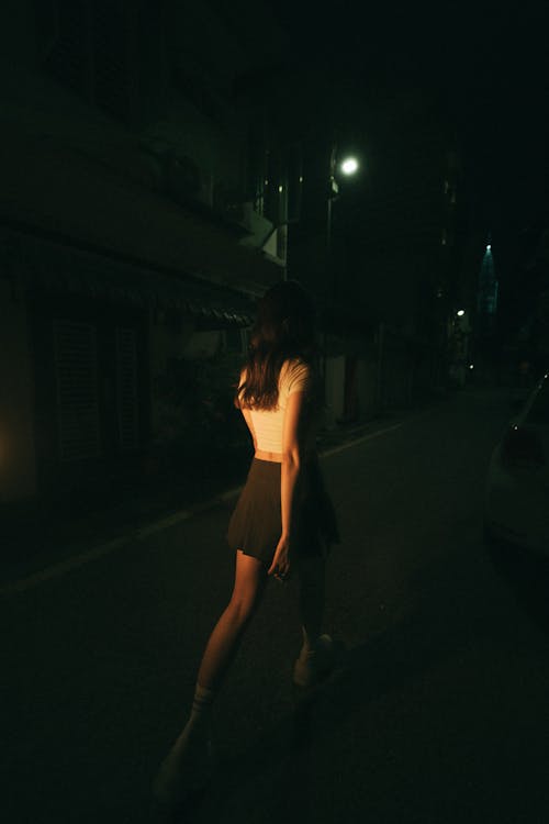 A woman in a skirt walking down a street at night