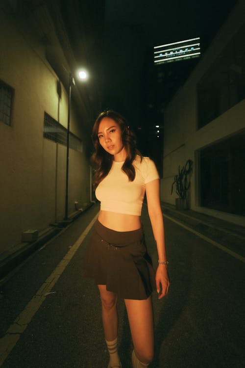 A woman in a skirt and crop top standing in the middle of a street