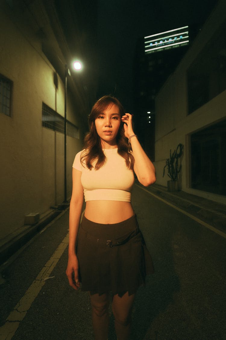 Young Woman In A Crop Top And Skirt Standing On A Street In City At Night 