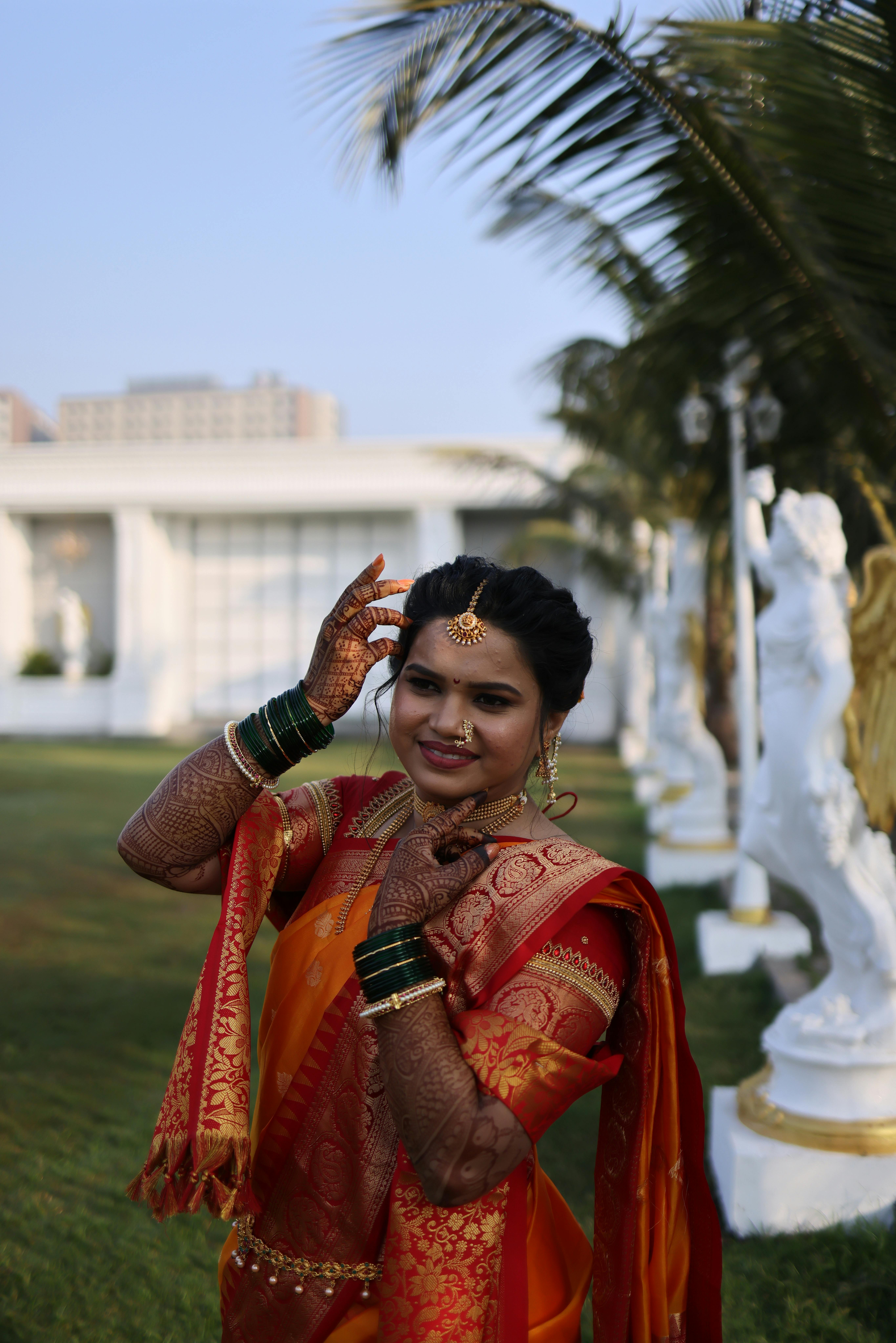 Free Woman in Indian attire with henna, posing outside a temple with palm trees. Stock Photo