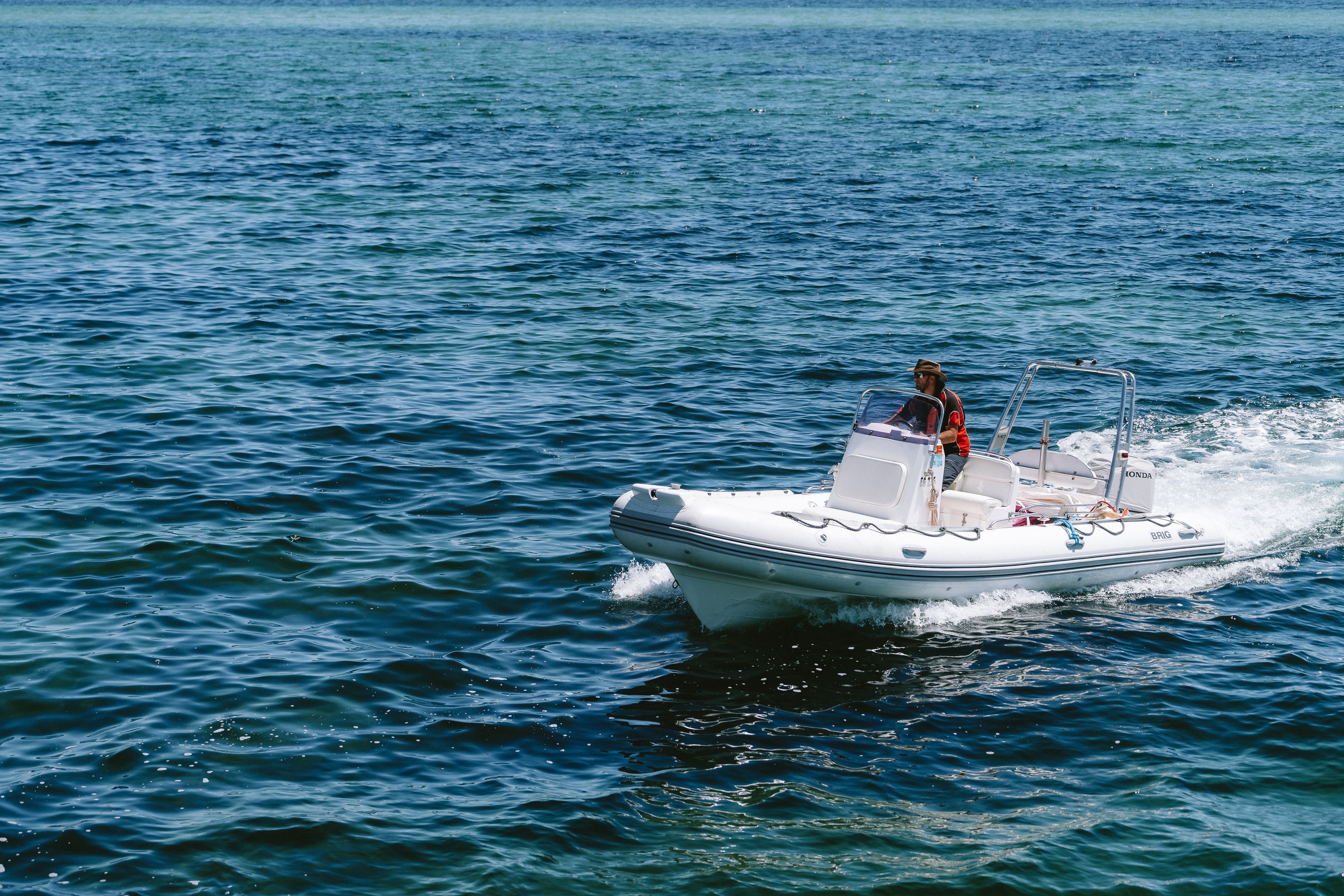A man riding in a small boat on the ocean · Free Stock Photo