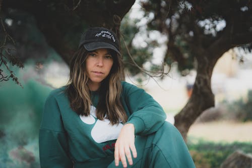 Woman Sitting in Green Pullover and Cap 