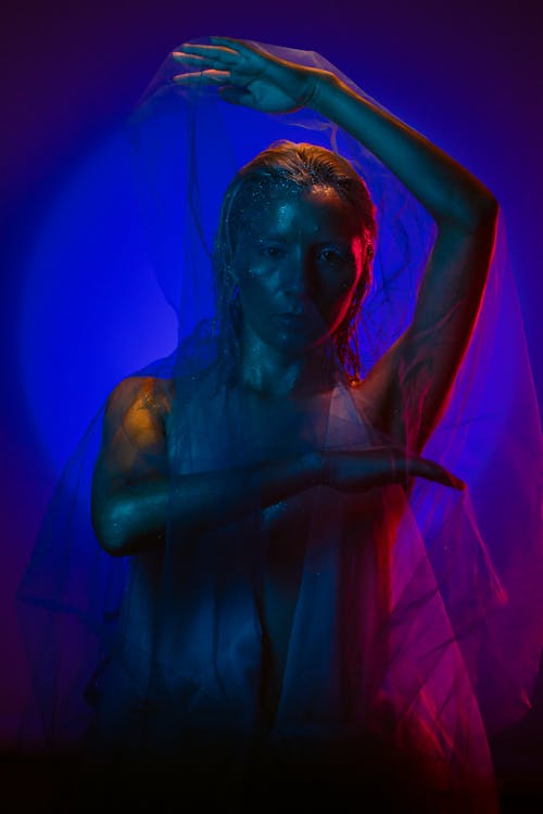 Modern, Artistic Studio Shot of a Woman with Shiny Skin Holding Tulle Fabric 