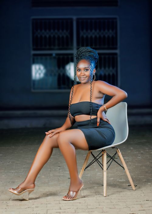 Free Stylish portrait of a young woman in black attire sitting outdoors in Malawi. Stock Photo