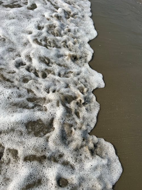 Close-up of a Foamy Wave Washing Up the Beach 