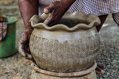 A person is making a pottery bowl with clay