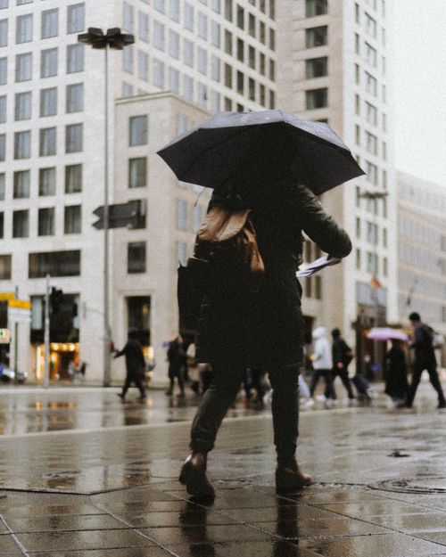 Free A person with an umbrella walking in rainy Berlin, creating a moody urban scene. Stock Photo