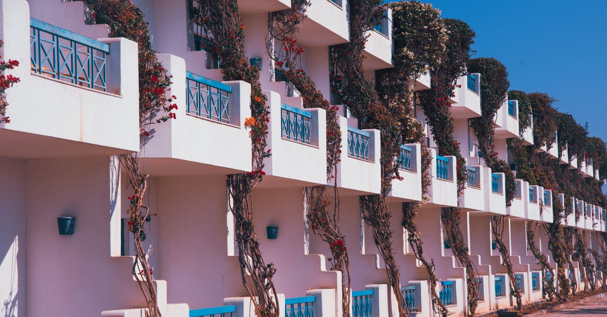 A vibrant modern apartment complex with ivy-covered balconies under bright blue skies.