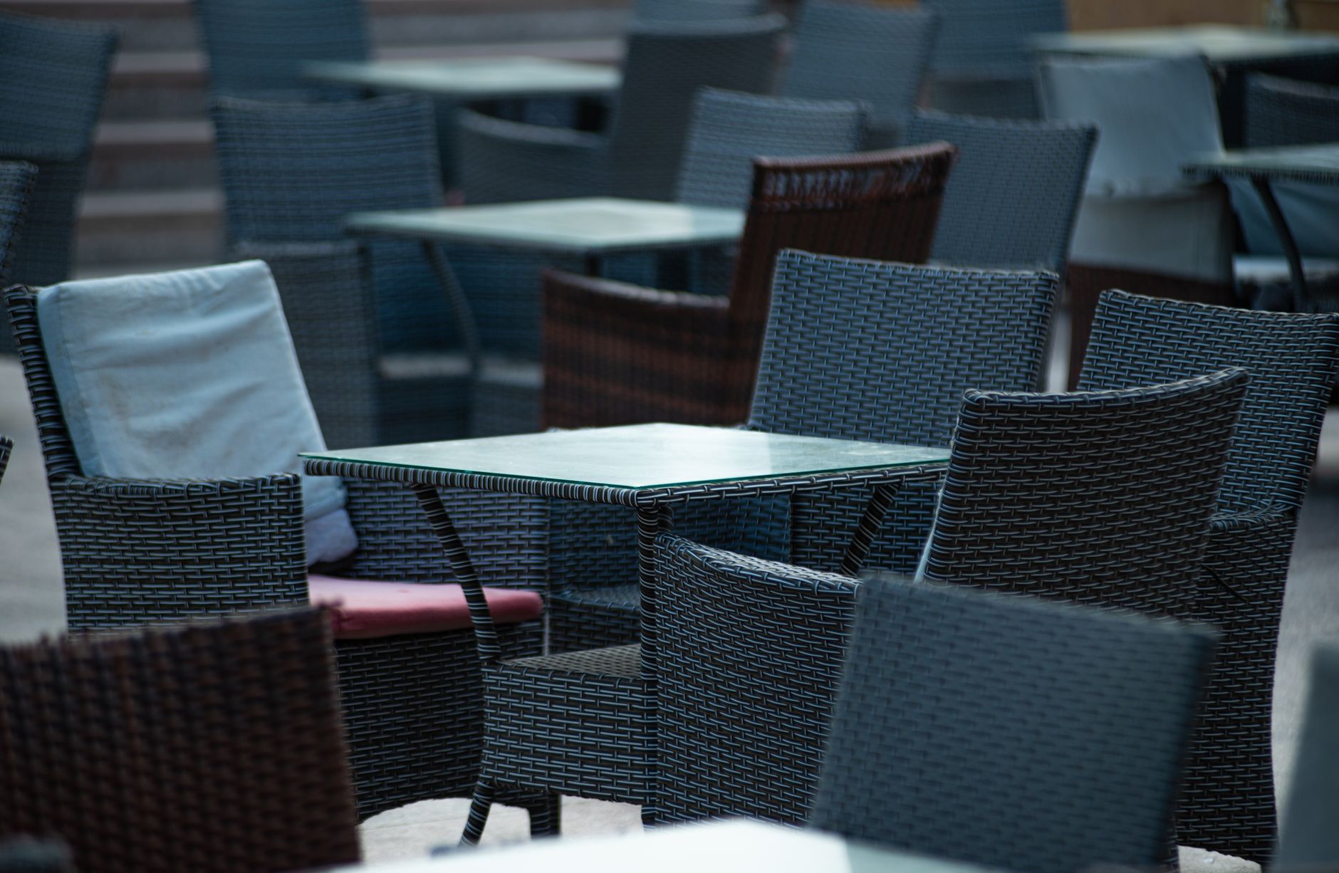 Empty outdoor terrace with wicker chairs and tables, creating a cozy café atmosphere.