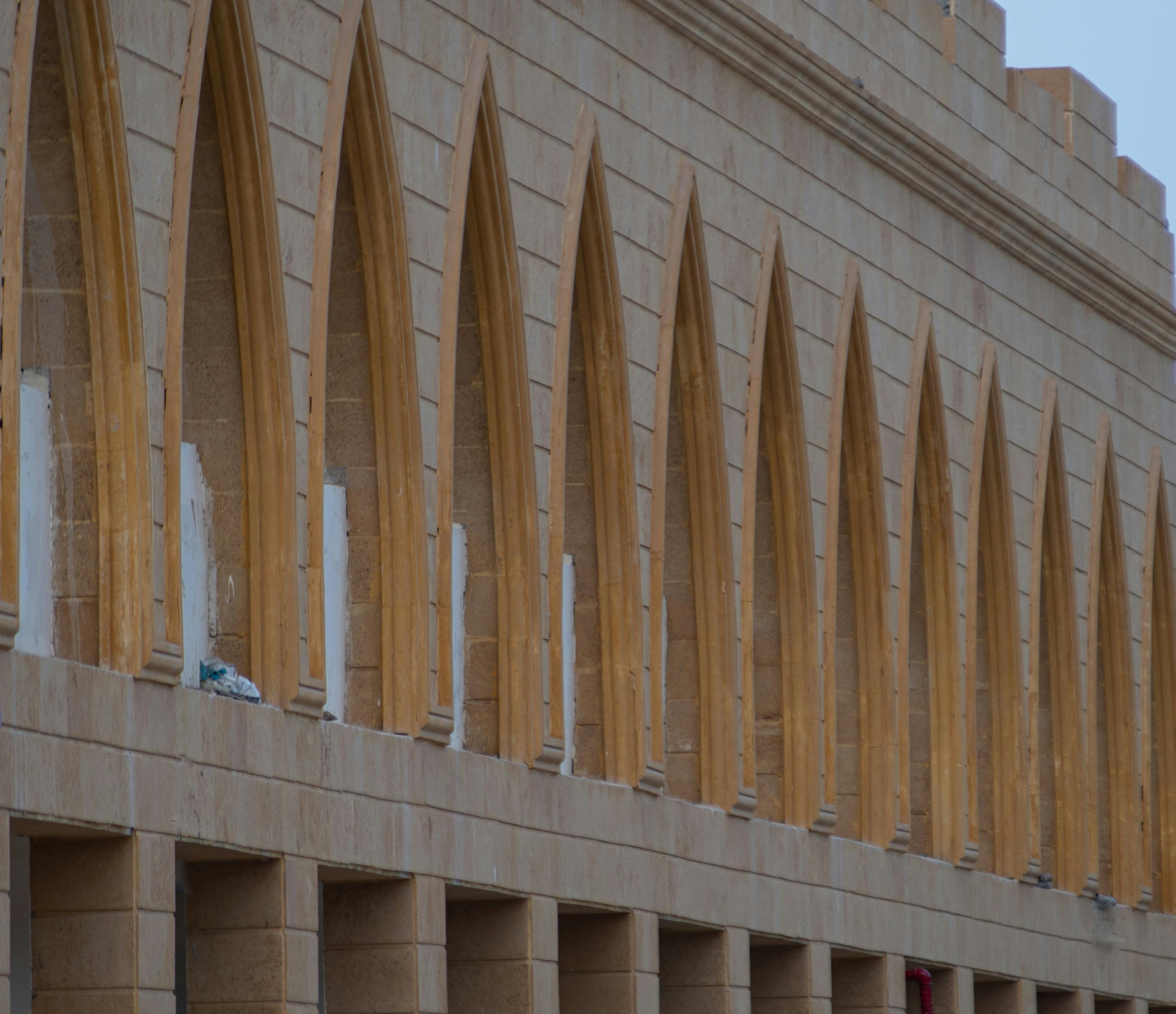 Striking facade of a sandstone building featuring a row of arched windows, showcasing architectural elegance.