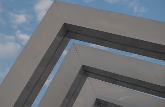 Abstract view of modern architecture with geometric patterns against a clear sky.